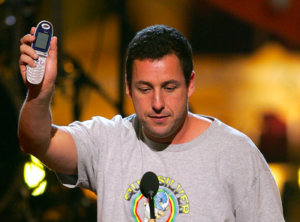 Adam Sandler proudly holds up at flip phone at the 2005 Teen Choice Awards